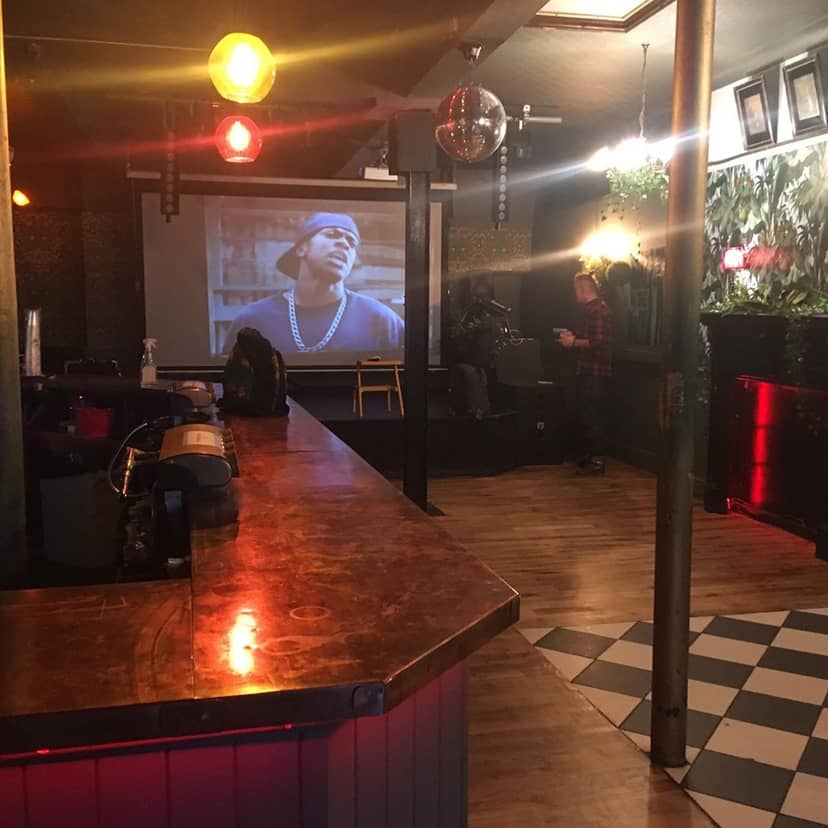 Cozy event space at The Macbeth with large screen, ideal for networking and gatherings.