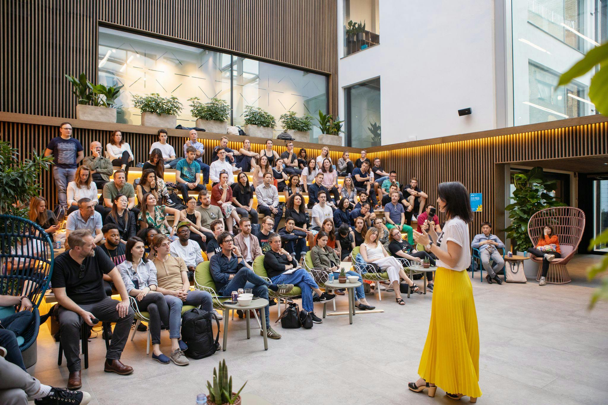 "Spitalfields Conservatory event space with engaged audience and lush greenery."