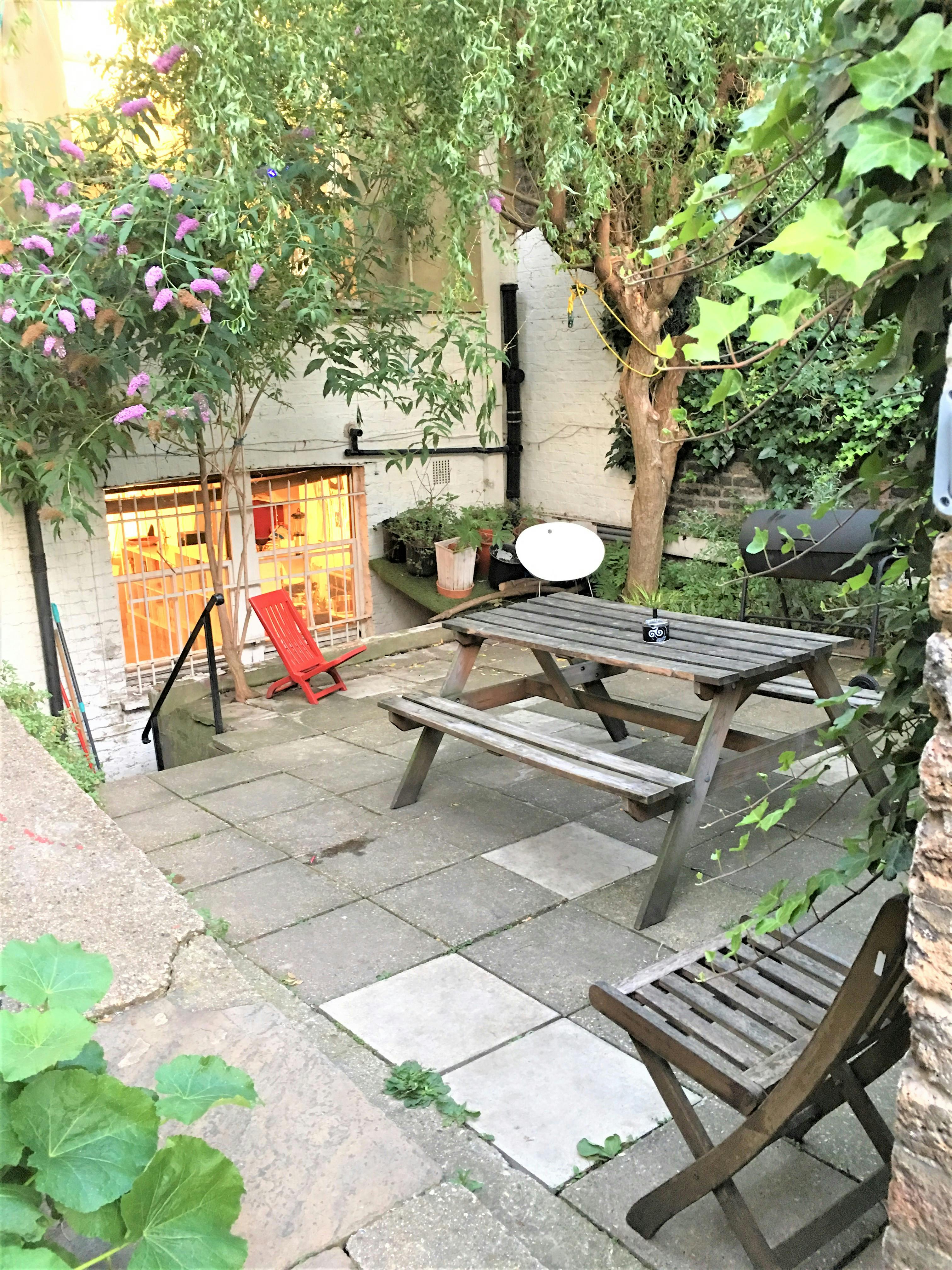 Charming outdoor venue in Dalston Den with rustic picnic table for networking events.