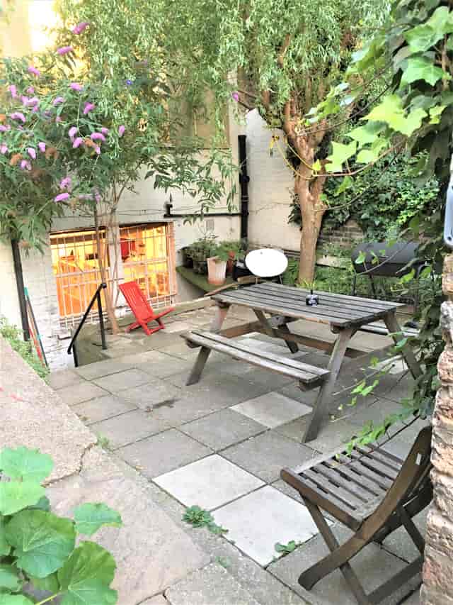 Charming outdoor venue in Dalston Den with rustic picnic table for meetings and events.