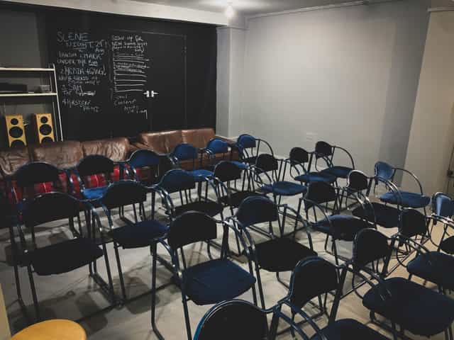 Minimalist event space in AE Studio with blue chairs for meetings and workshops.