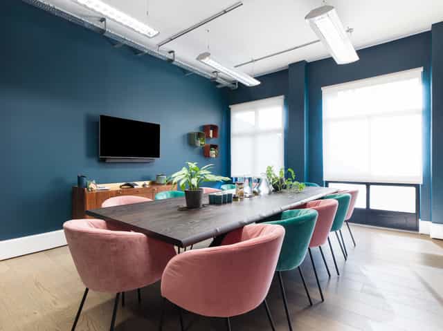 Modern conference room with pastel chairs and teal walls, ideal for meetings or events.