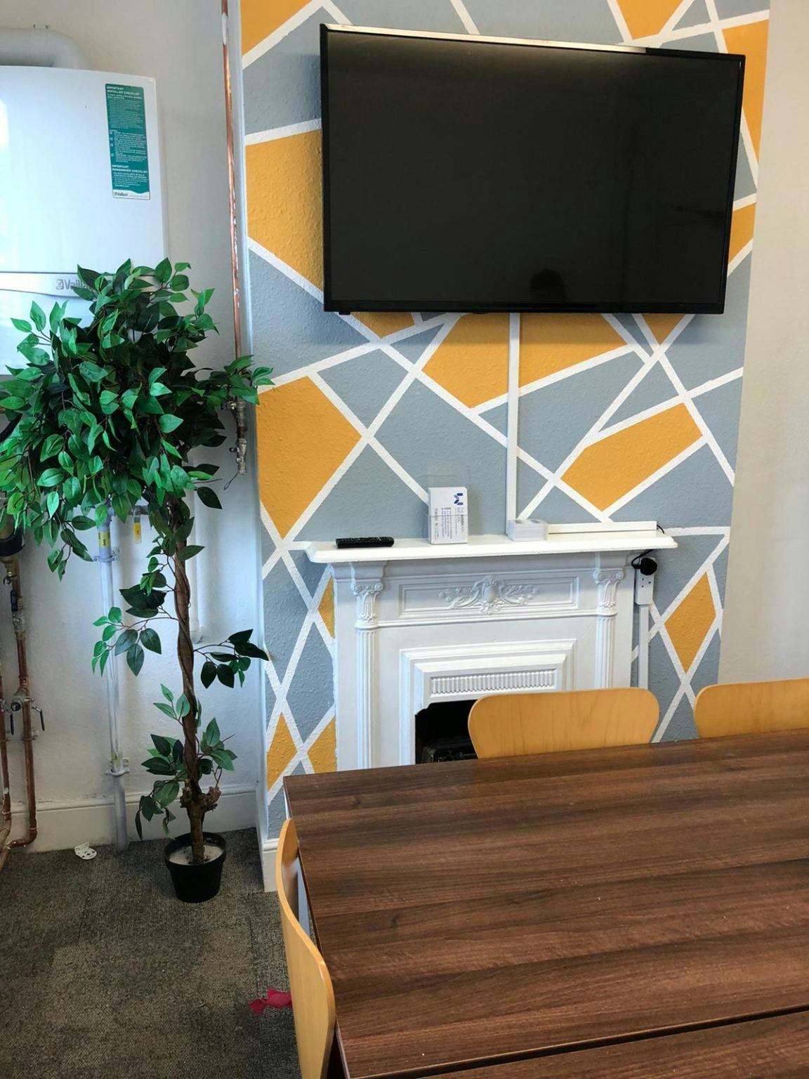 Modern meeting space in The Workary Welling with geometric accent wall and wooden table.