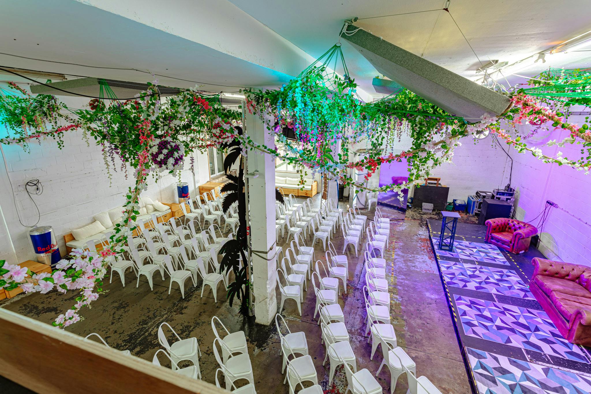 Summer party venue with white chairs, vibrant decor, and modern lighting.