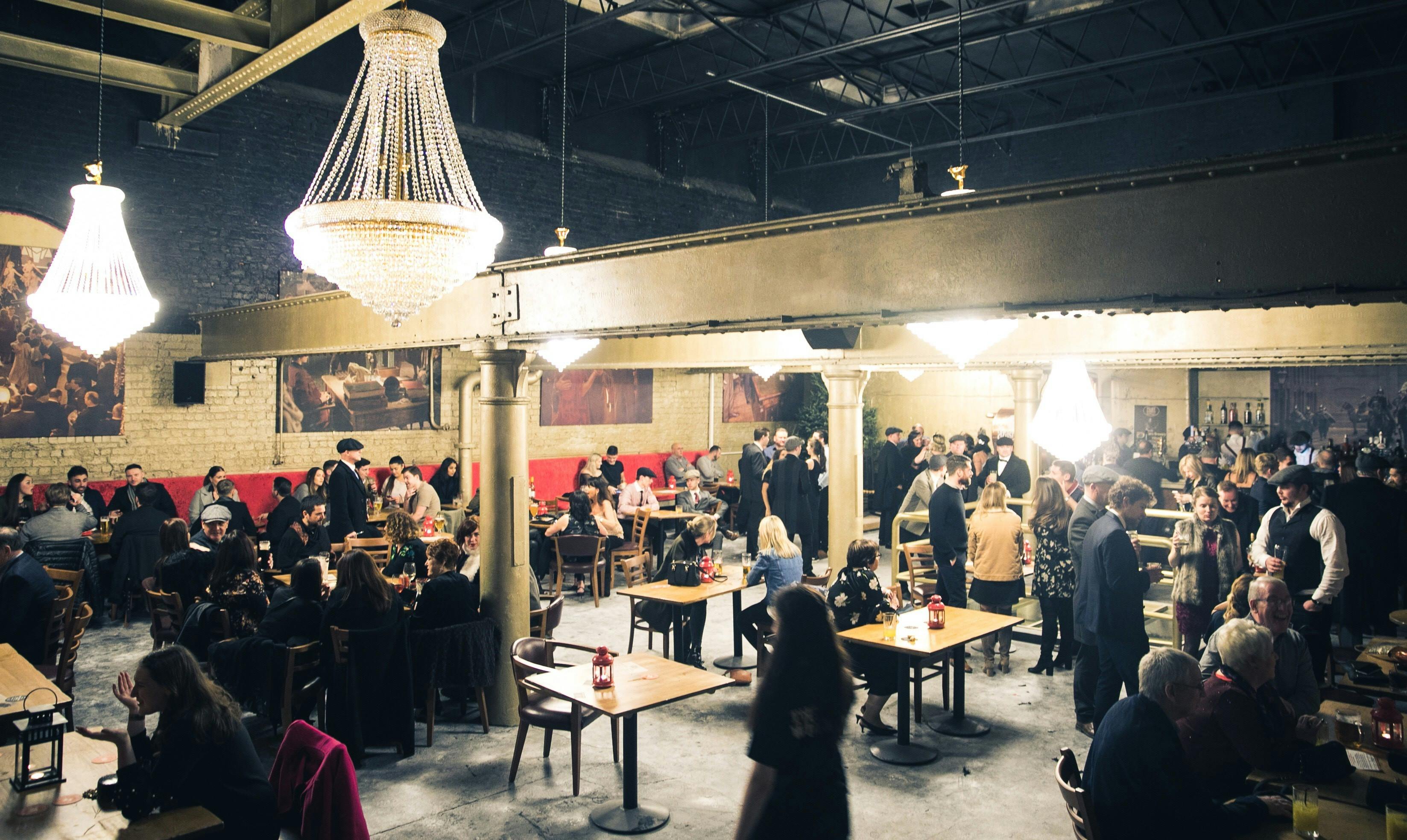 Upstairs bar in Peaky Blinders Liverpool, elegant chandeliers, vibrant event space for gatherings.