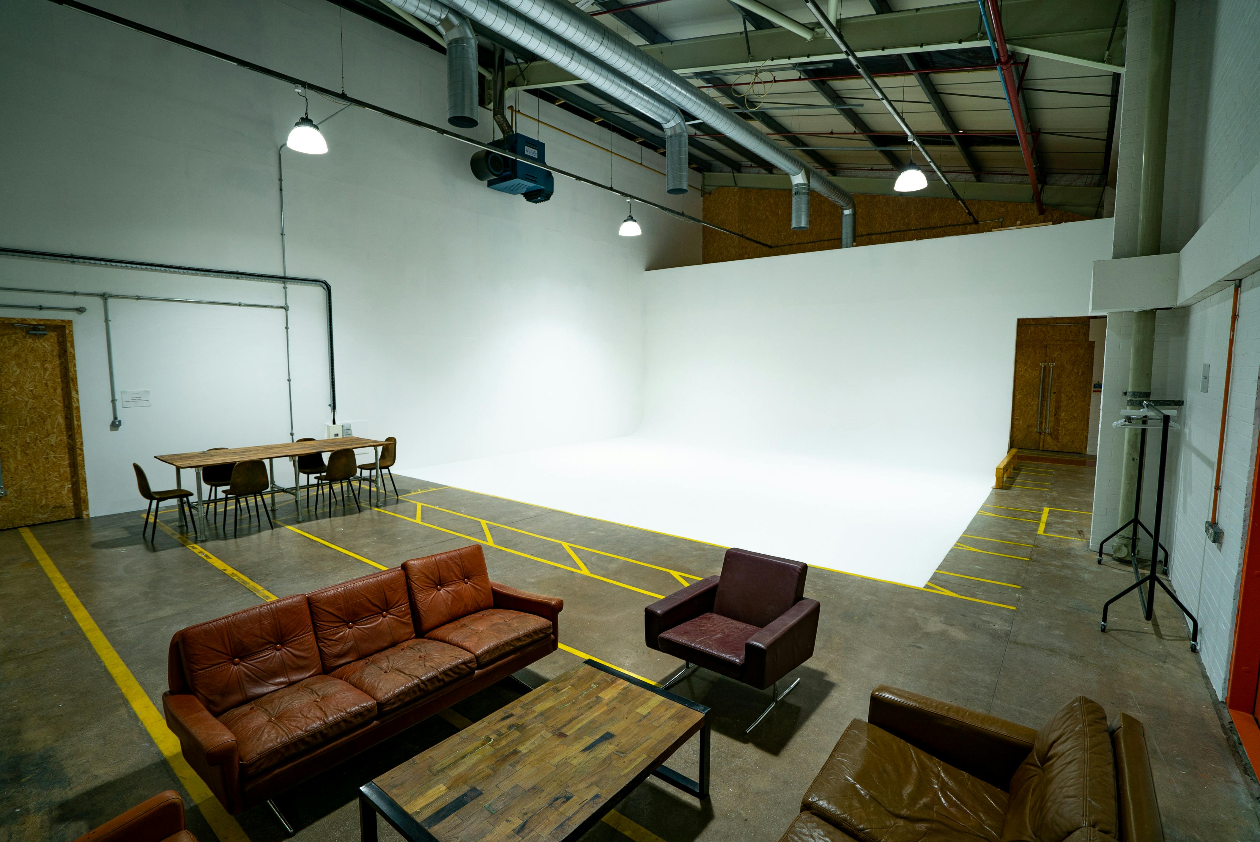 Versatile event space with white backdrop, ideal for meetings and presentations.