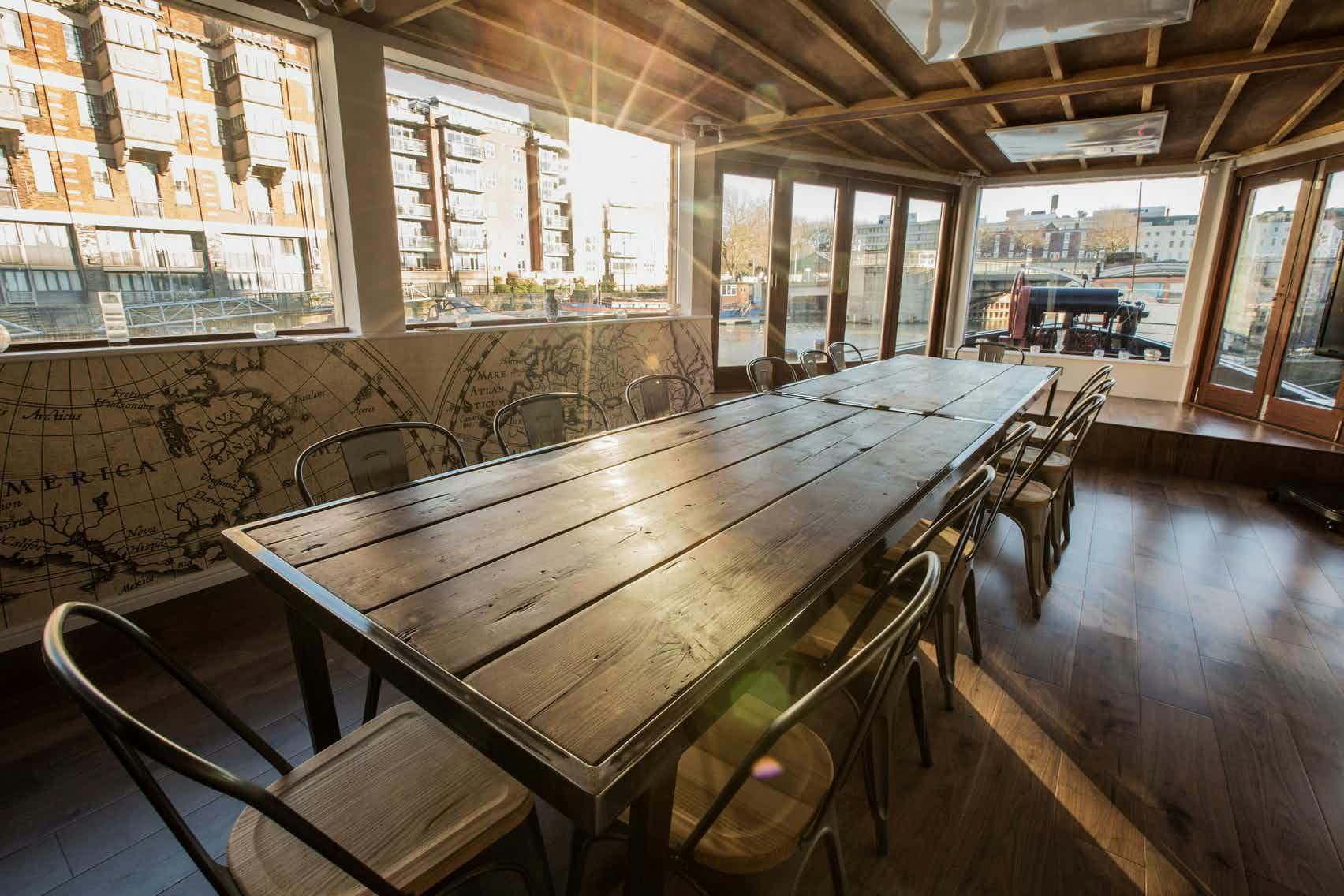 Spacious meeting room with wooden table and natural light at THE BRIDGE, Floating Harbour.