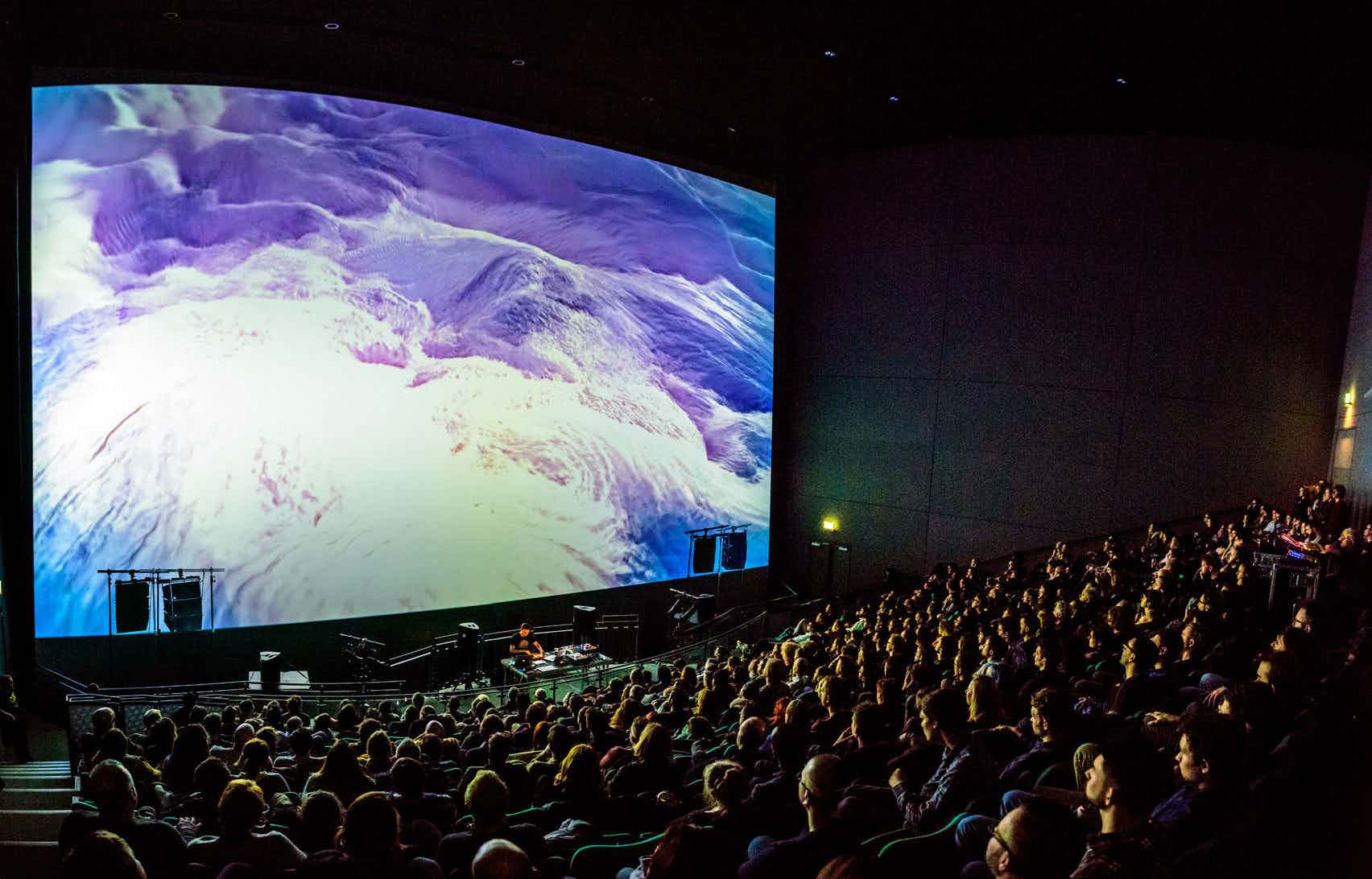 Audience at Bristol Aquarium theater enjoying a vibrant multimedia presentation. - Banner