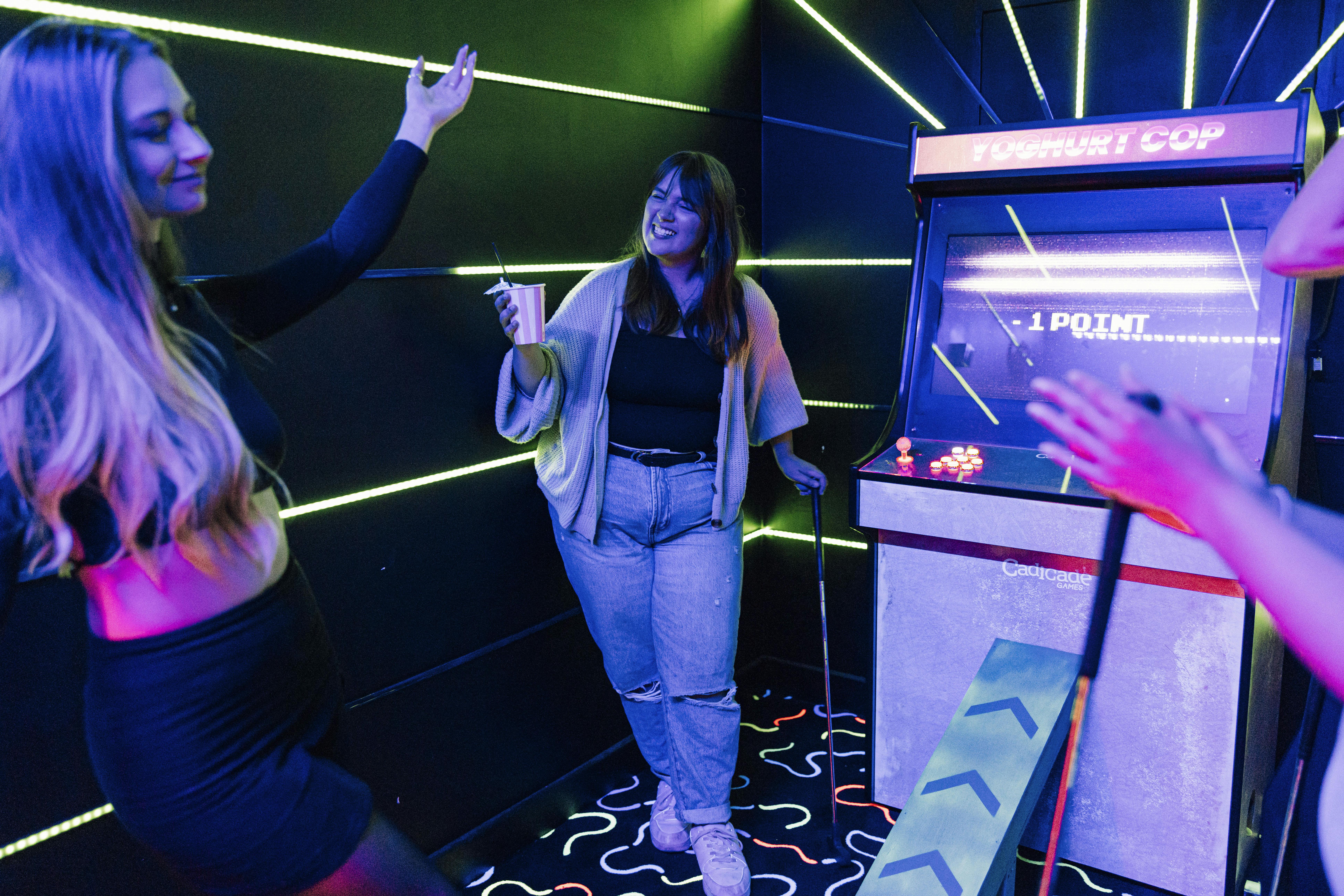Vibrant event space with neon lights and arcade games for team-building activities.