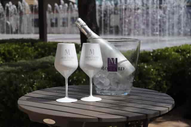 Elegant outdoor event setup with champagne, glasses, and fountain ambiance.