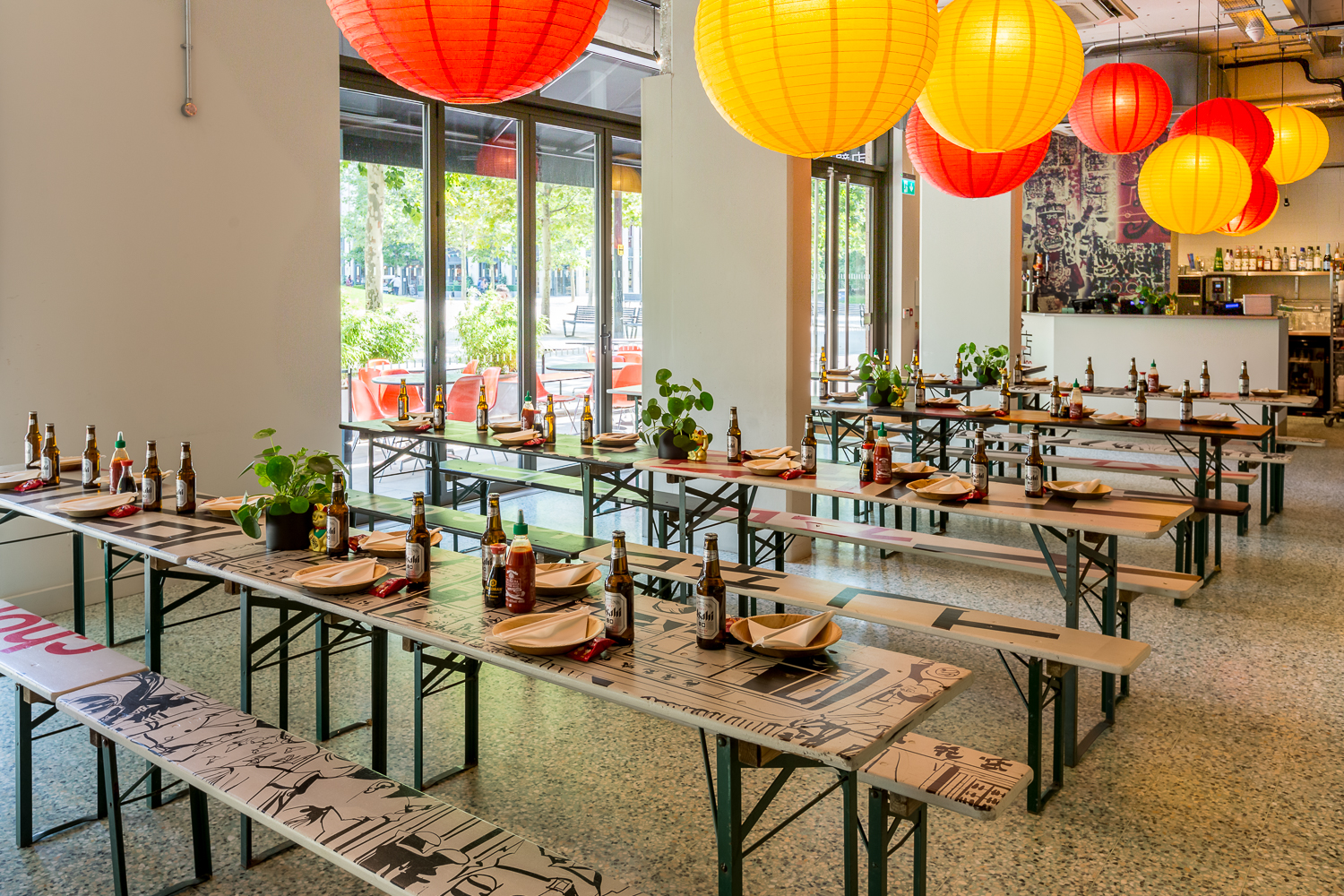 Vibrant event space with communal tables and colorful lanterns for gatherings. - Banner
