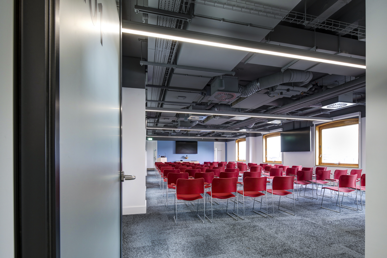 Modern meeting room with red chairs, ideal for conferences and workshops. - Banner
