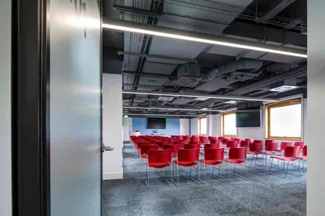 Modern meeting room with red chairs, ideal for conferences and workshops.