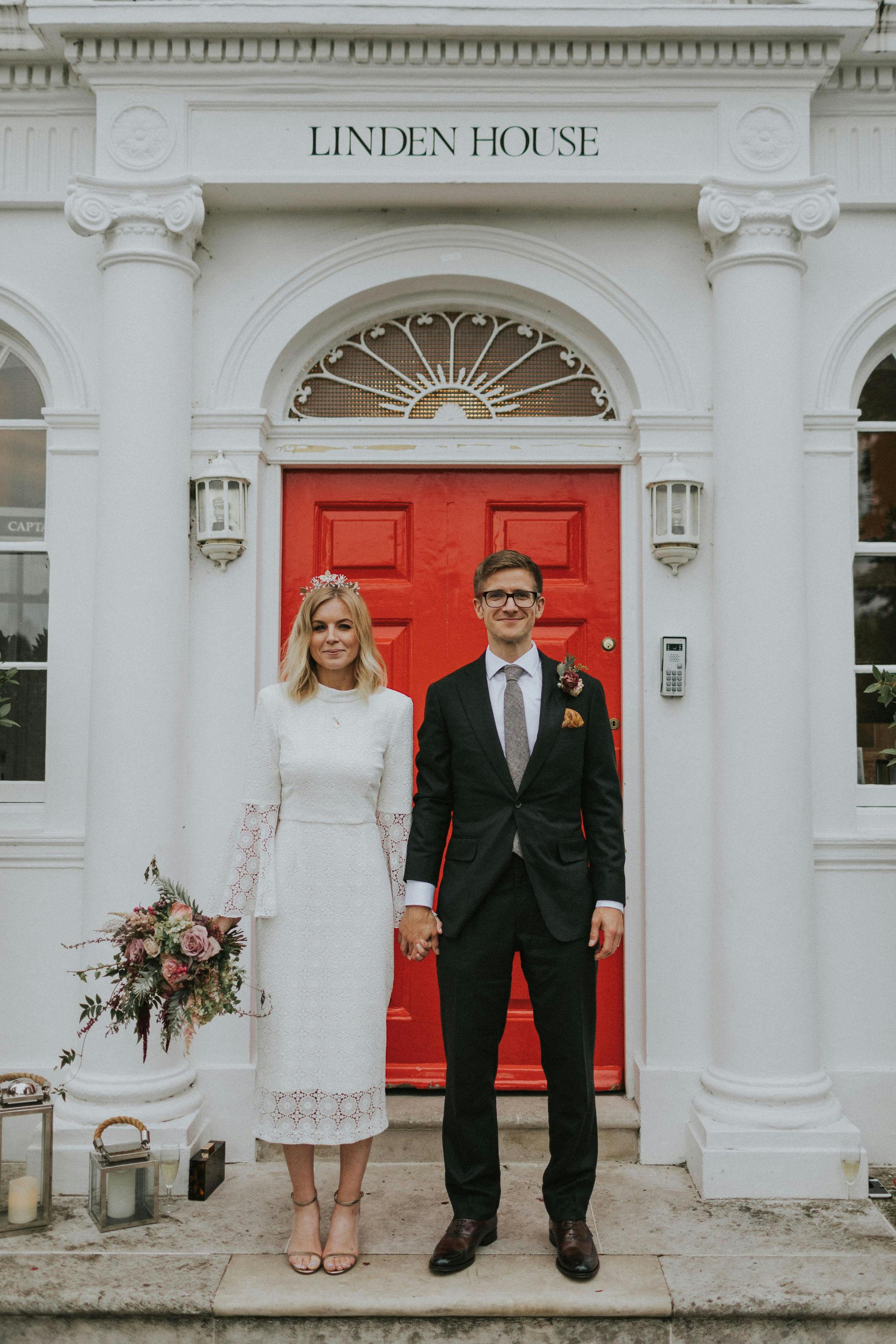 Stylish couple by vibrant red door at Linden House, perfect for weddings and events.