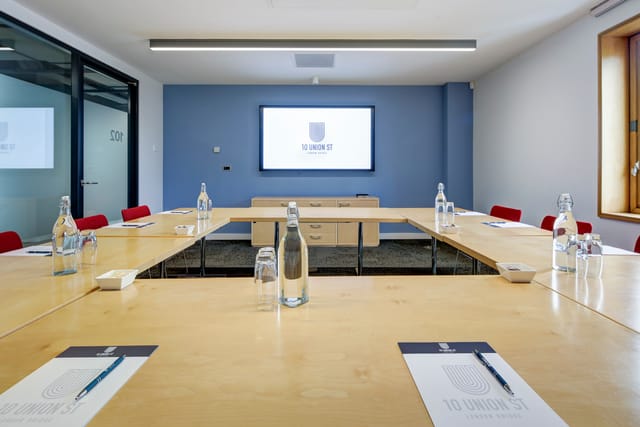 Modern meeting room with wooden table and red chairs, perfect for corporate workshops.