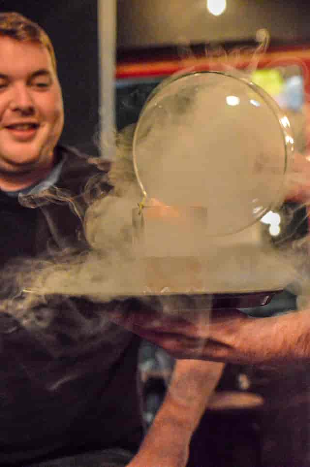 Creative cocktail presentation with smoke under glass dome at BATCH Cocktail Bar.