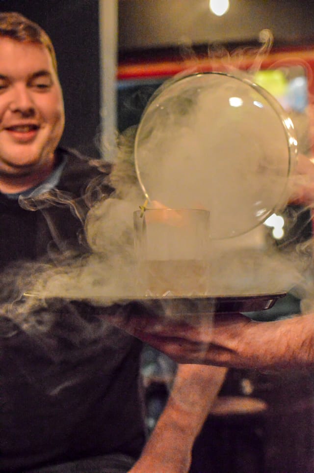 Creative cocktail presentation with smoke under glass dome at BATCH Cocktail Bar.