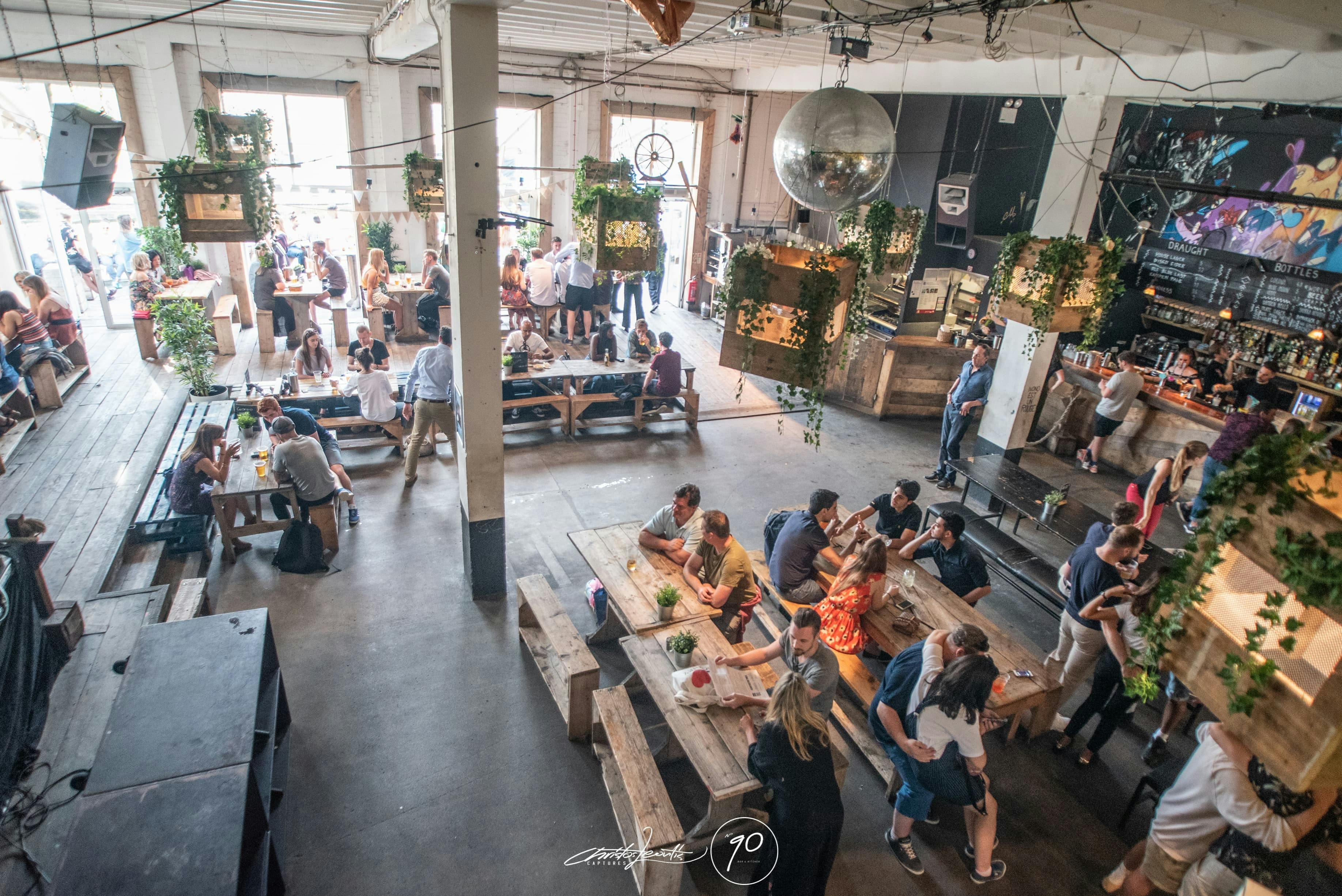 Vibrant event space at 90 Bar & Kitchen with communal seating and disco ball.