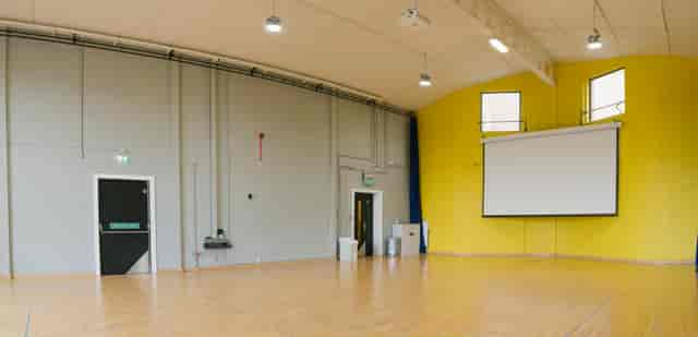 Versatile event space with wooden floor and yellow wall for workshops and presentations.