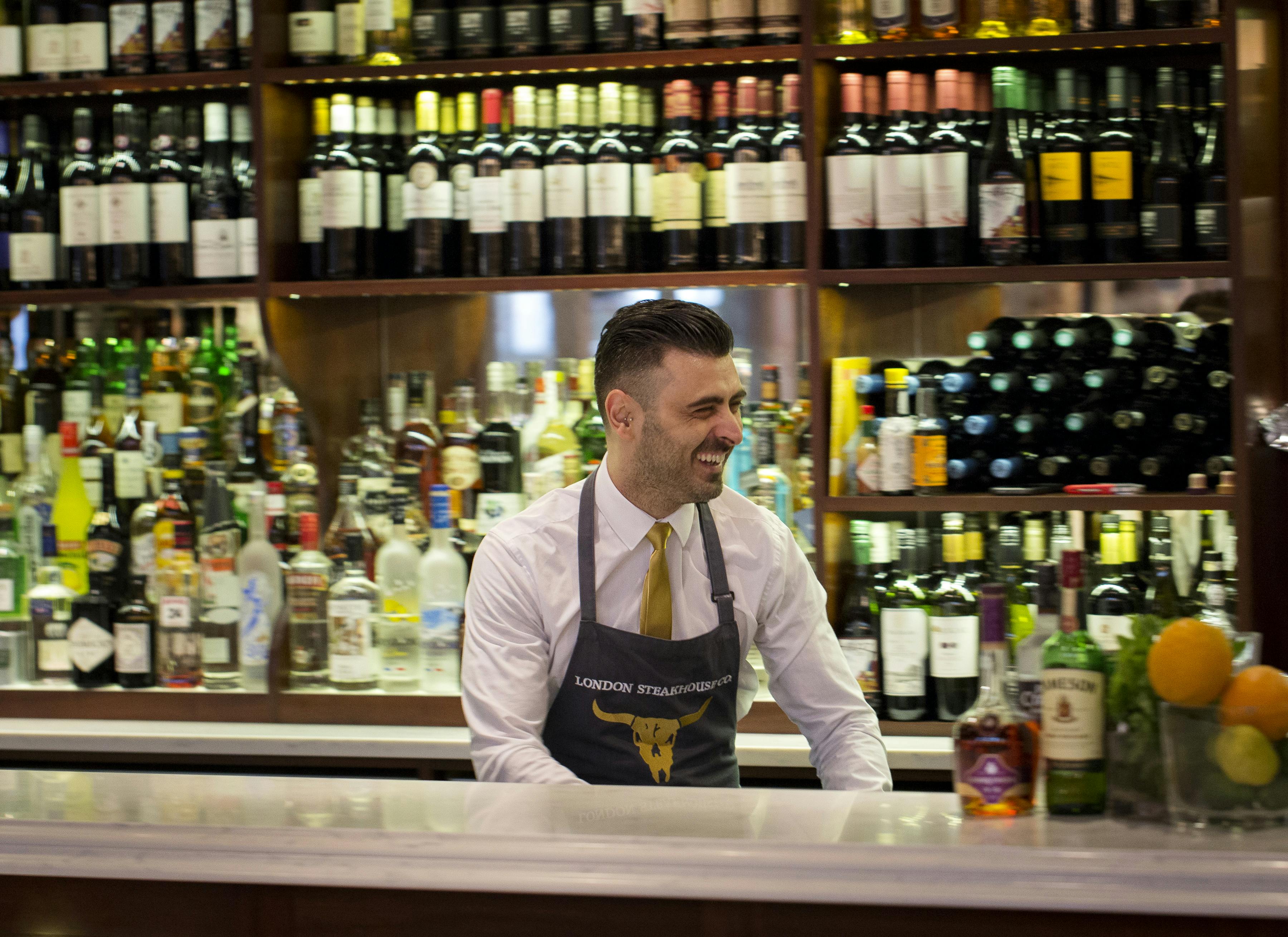 Well-dressed bartender in stylish London steakhouse bar, perfect for events and gatherings.