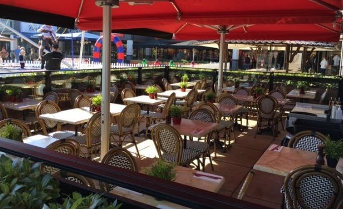 Outdoor dining area at Café Rouge Cheshire Oaks with red umbrellas, ideal for summer events.