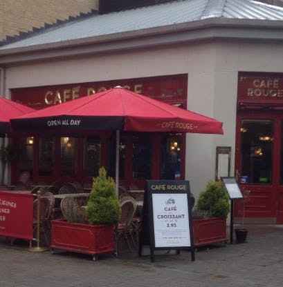 Charming outdoor café venue with red umbrellas, perfect for casual meetings and networking.