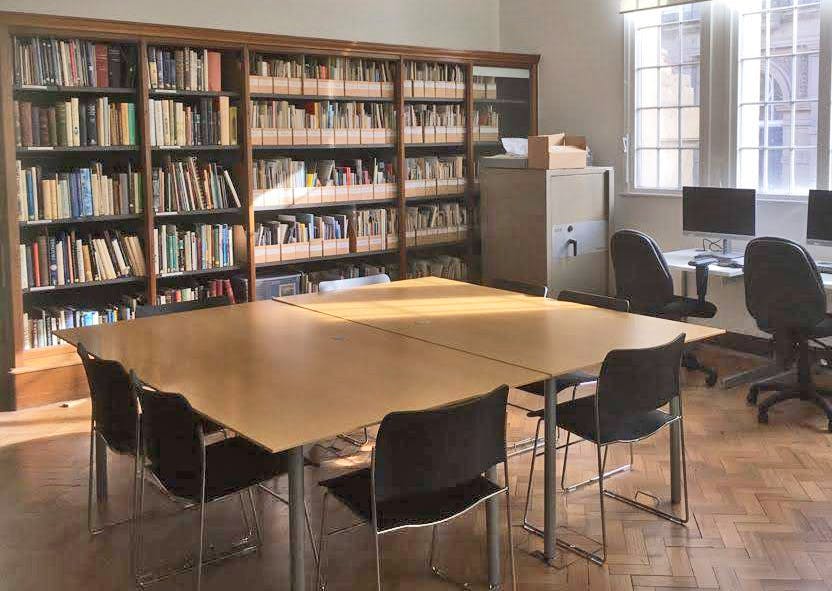 Library meeting room with central table, bookshelves, ideal for discussions and presentations.