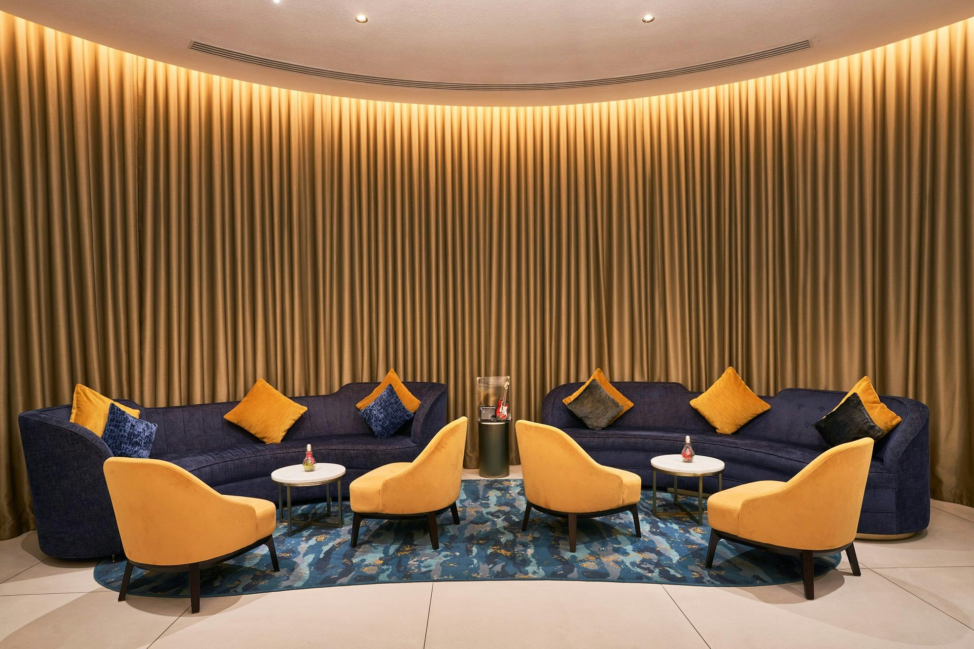 Stylish lounge with yellow chairs and blue sofa for networking at SOUND Cafe after party.