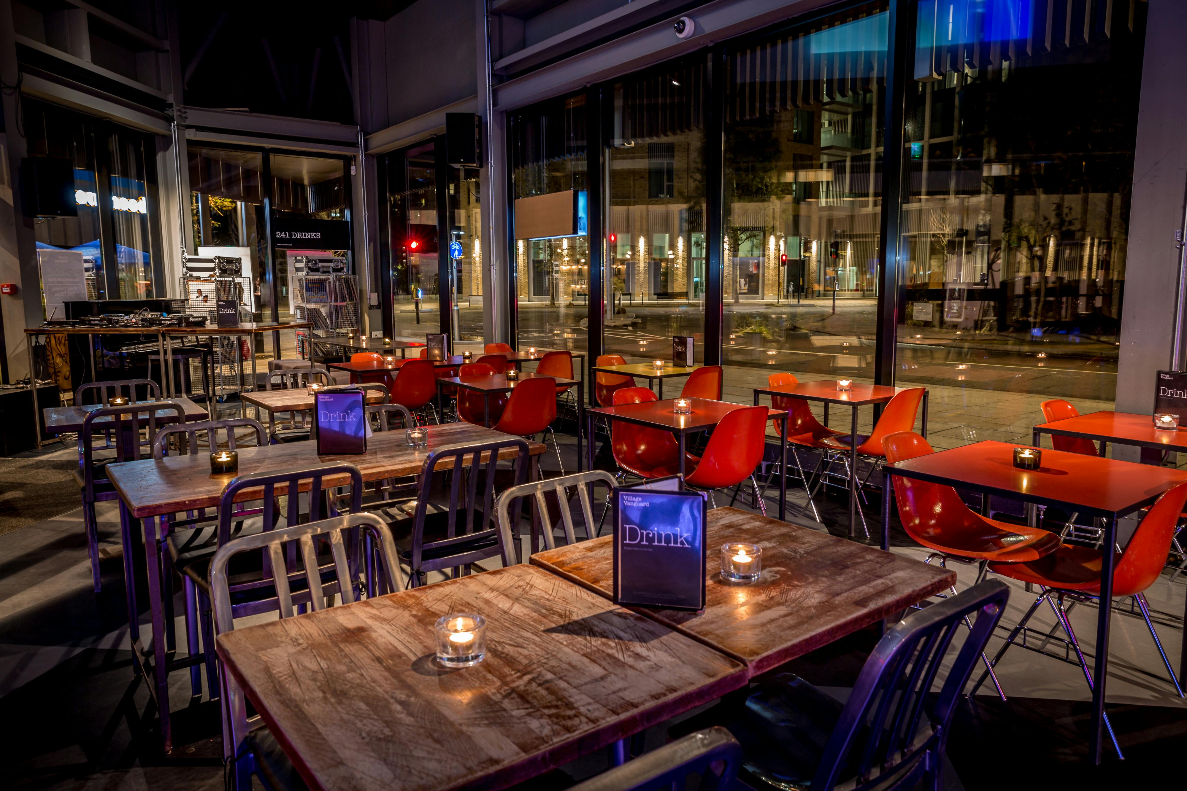 Modern event space with wooden tables and red chairs, perfect for gatherings and networking.