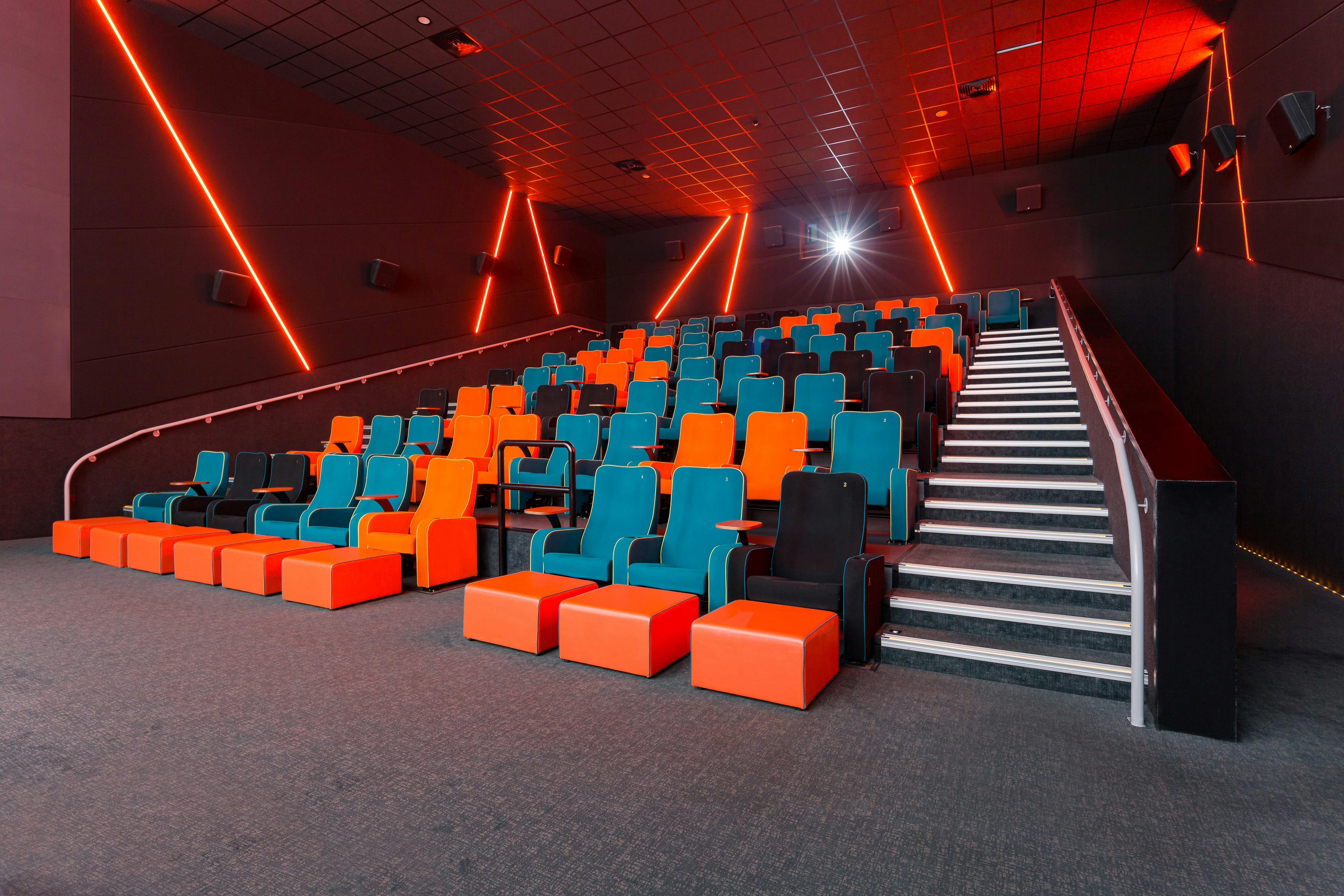 Modern cinema auditorium with teal and orange seating, perfect for film premieres and events.