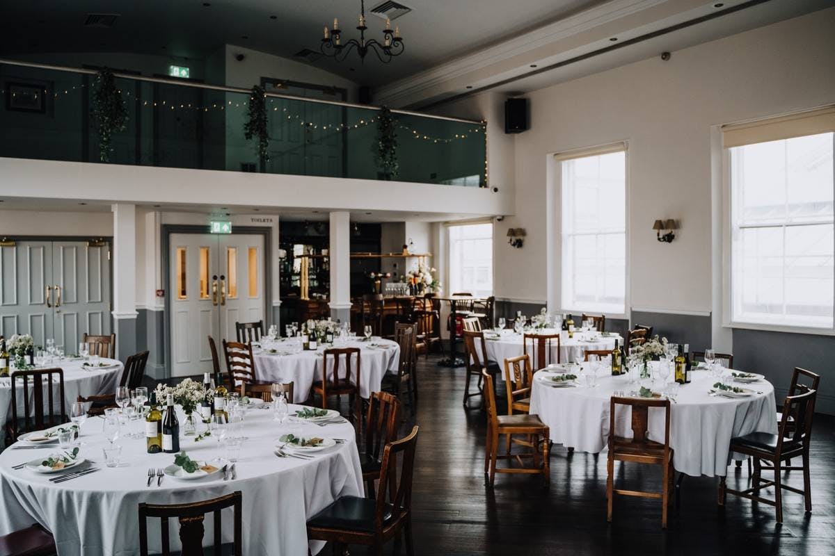 Elegant wedding venue with round tables, fresh flowers, and soft lighting.