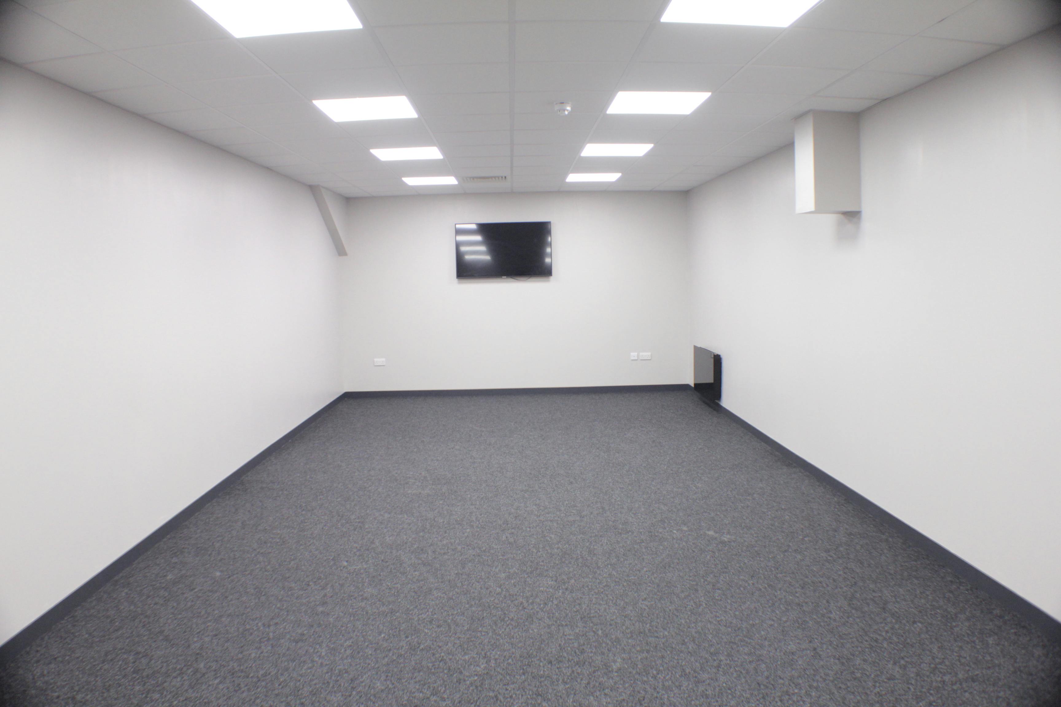 Spacious blank meeting room with wall-mounted screen for conferences and brainstorming.