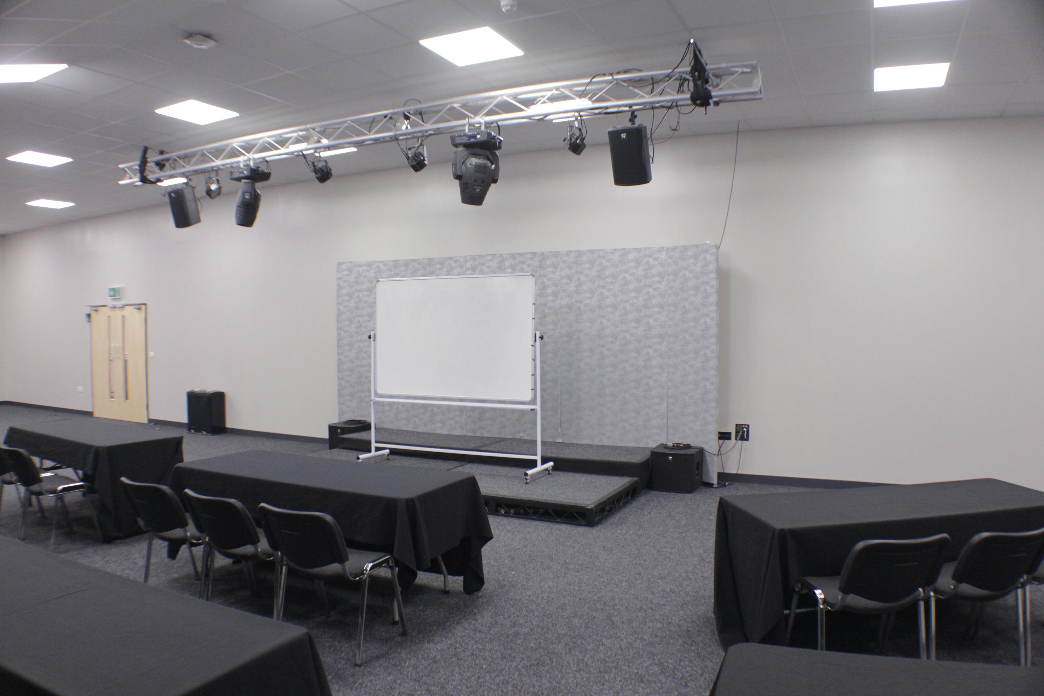 Versatile meeting room with raised stage, ideal for presentations and workshops.