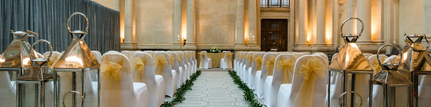 Elegant wedding ceremony space with gold-sashed chairs and floral decor in Bristol Harbour Hotel.