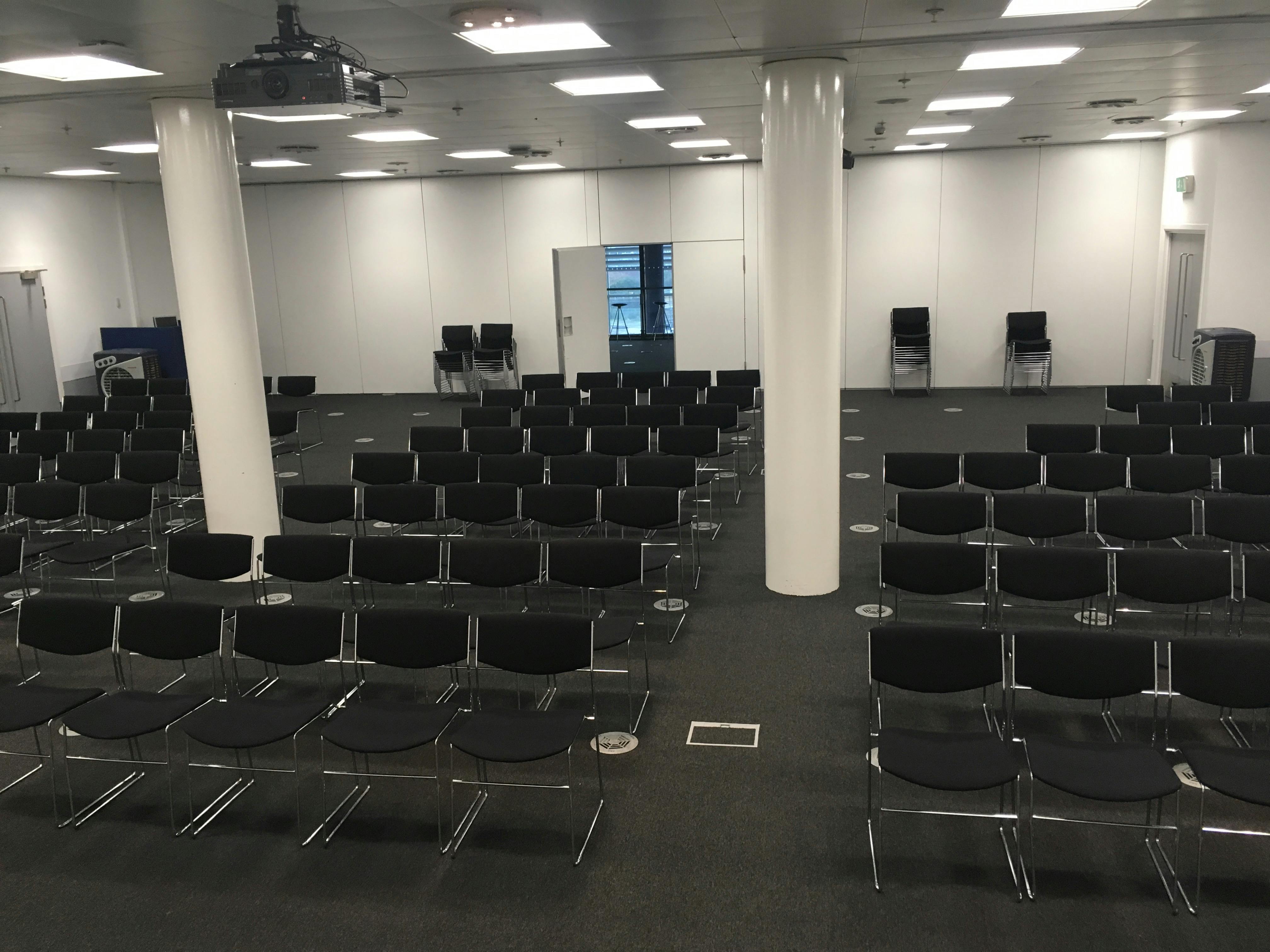 Spacious event suite with black chairs, perfect for presentations and seminars.