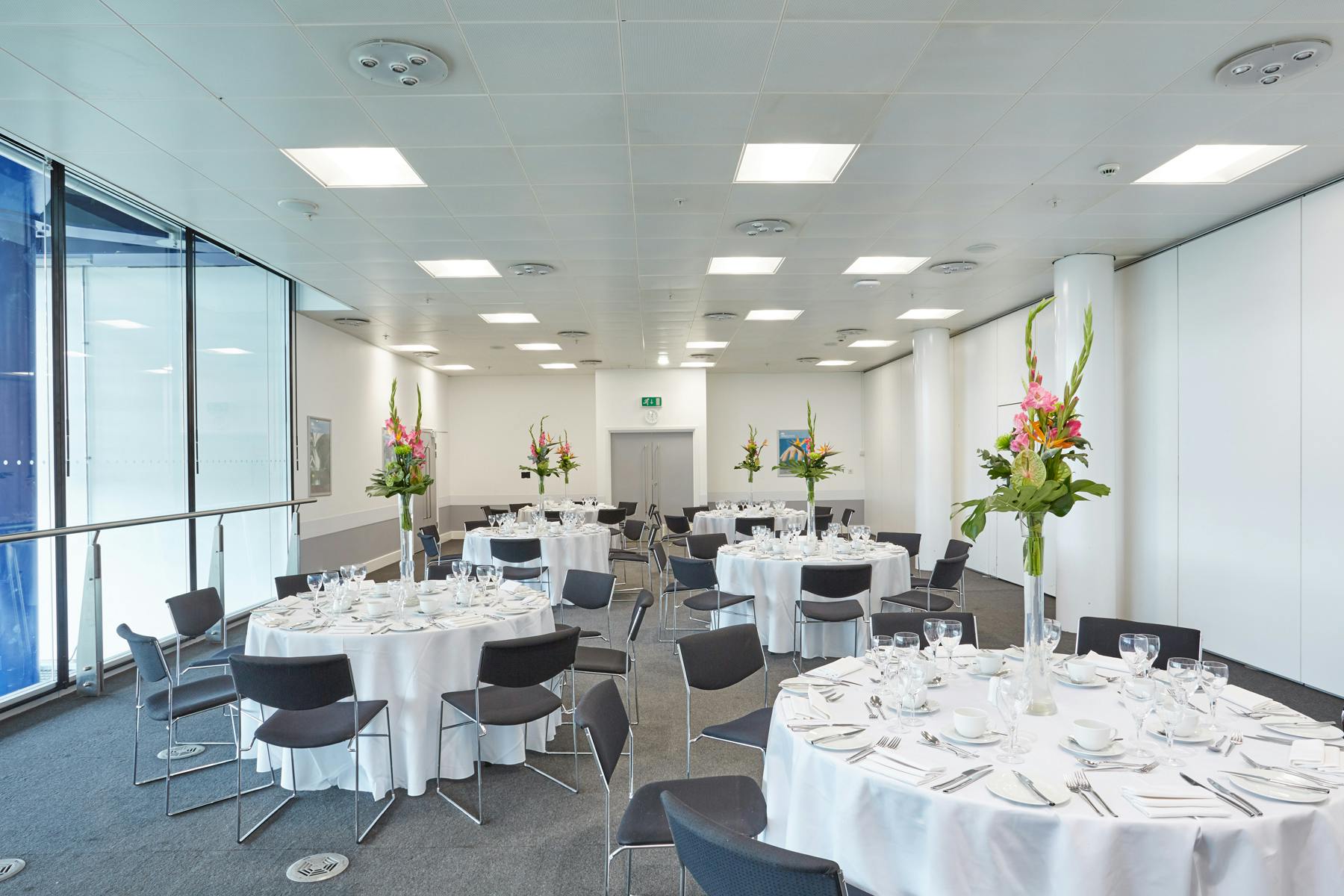 Elegant event suite with round tables and floral centerpieces, perfect for corporate meetings.