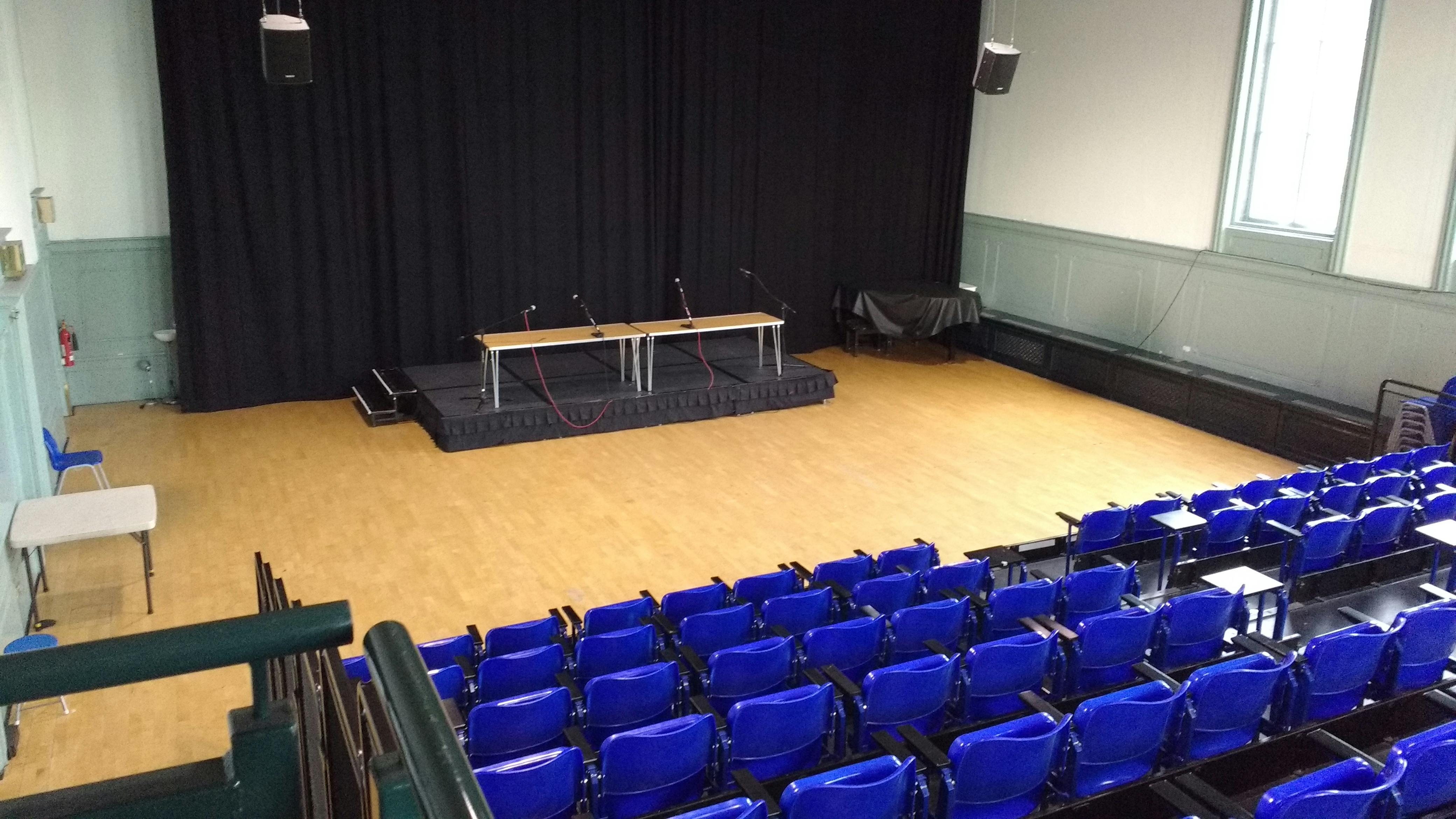 Main Hall at Wac Arts, featuring blue chairs for corporate presentations and panel discussions.