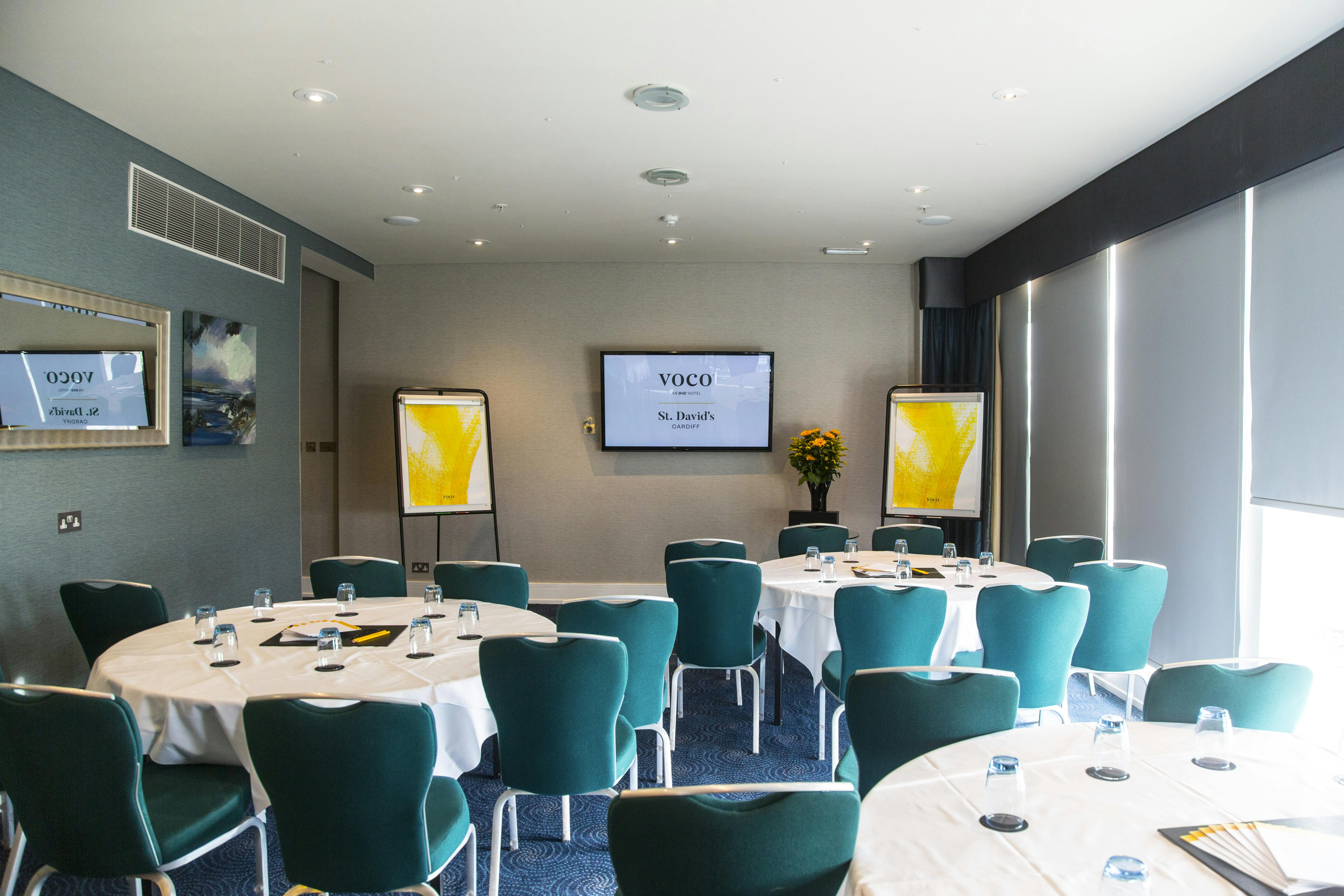 Penarth Suite at Voco St David's: modern meeting room with round tables for corporate events.