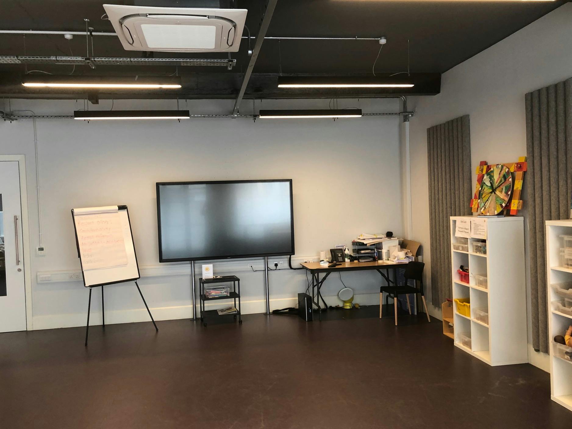 Versatile training room with large screen, ideal for workshops and team meetings.