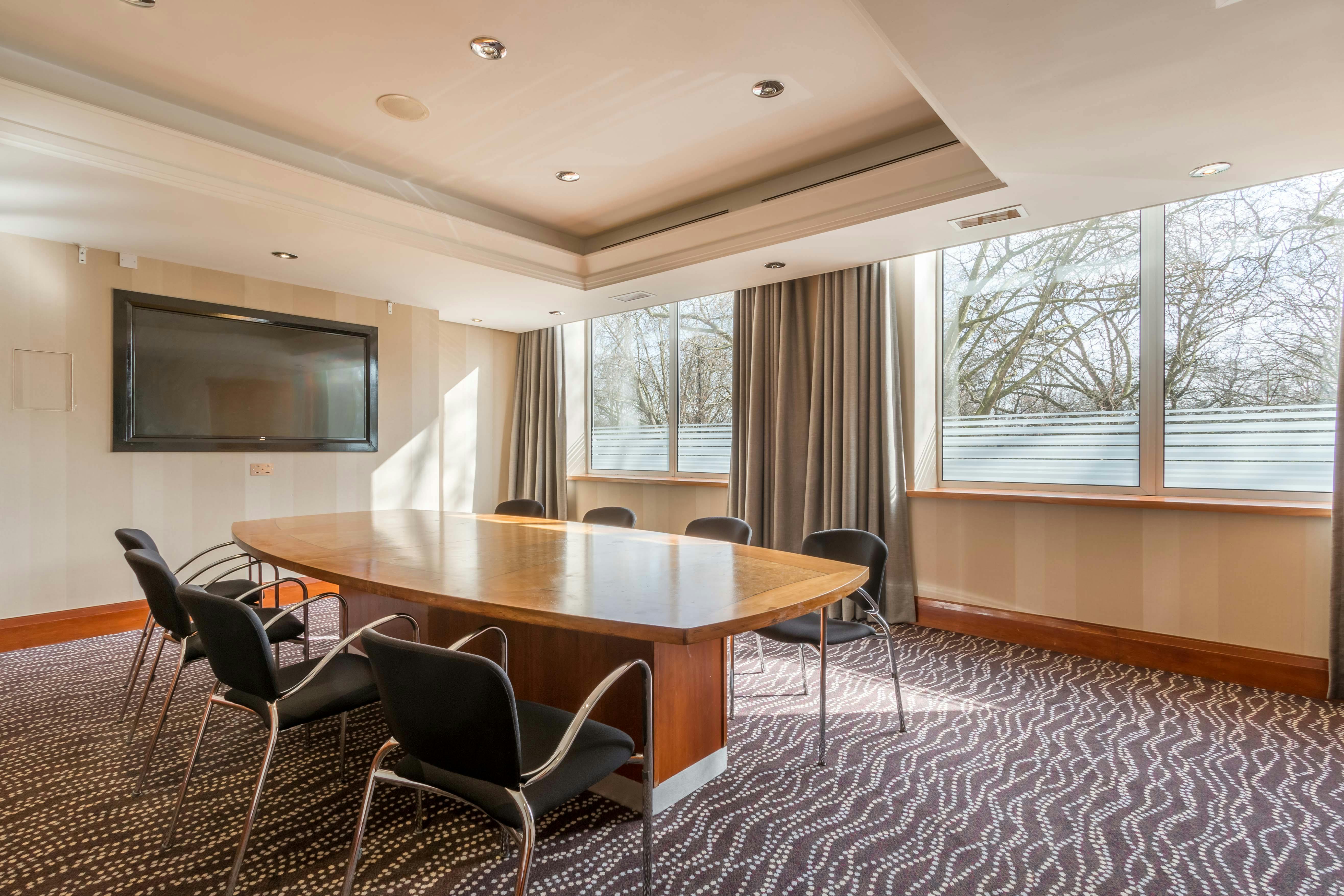 Boardroom Meeting Room at Thistle Kensington Gardens with large wooden table, ideal for conferences.