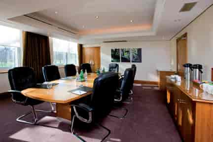 Boardroom Meeting Room at Thistle Kensington Gardens with large wooden table, ideal for conferences.