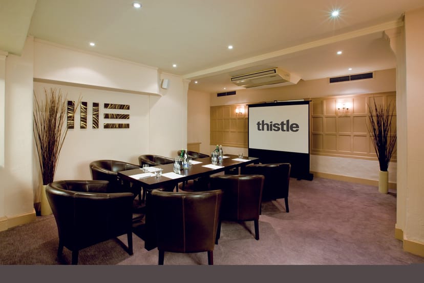Meeting room with leather chairs and large screen at Thistle Bloomsbury Park.
