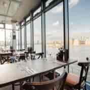 Stylish waterfront restaurant with large windows, perfect for events and gatherings.