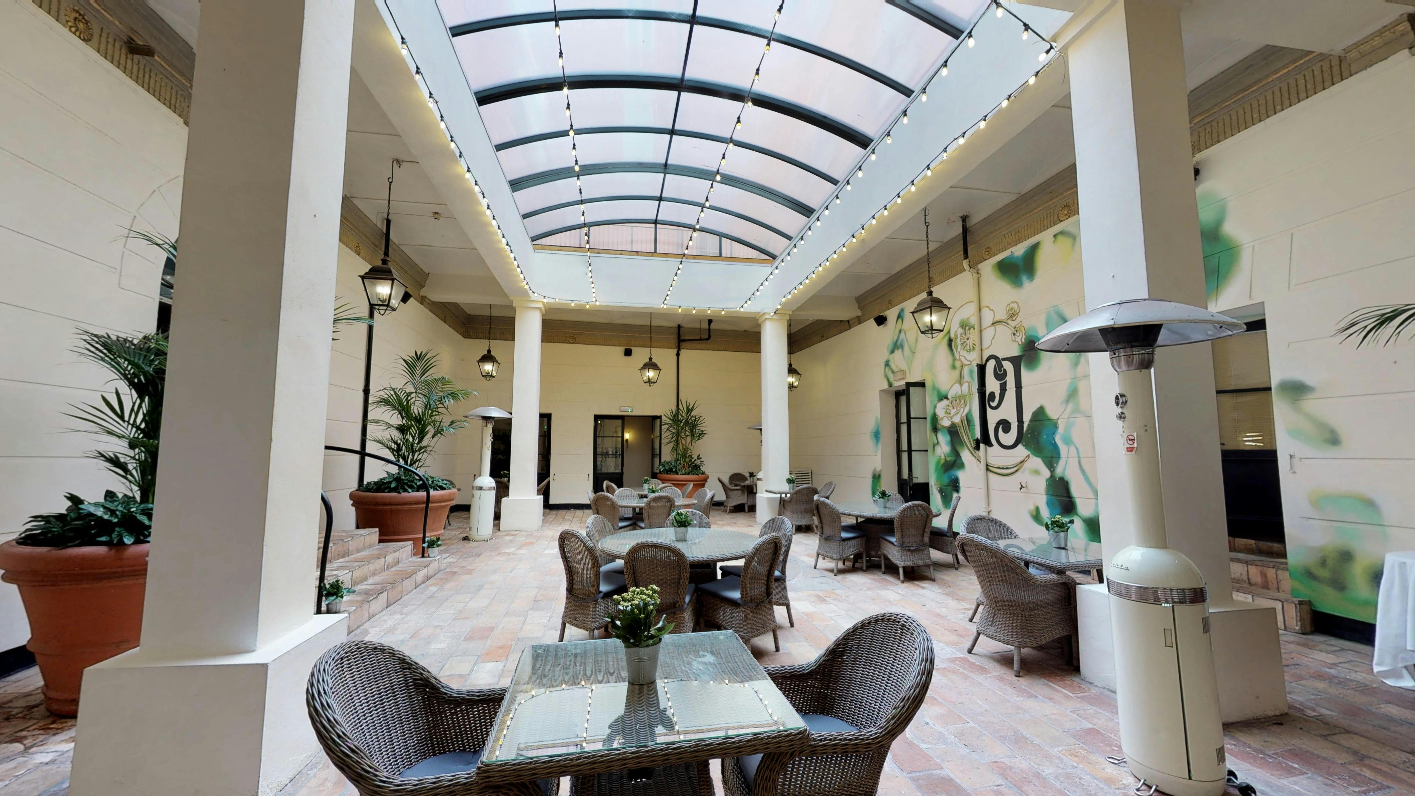 Indoor-outdoor event space at Hotel du Vin Birmingham with glass ceiling and greenery.