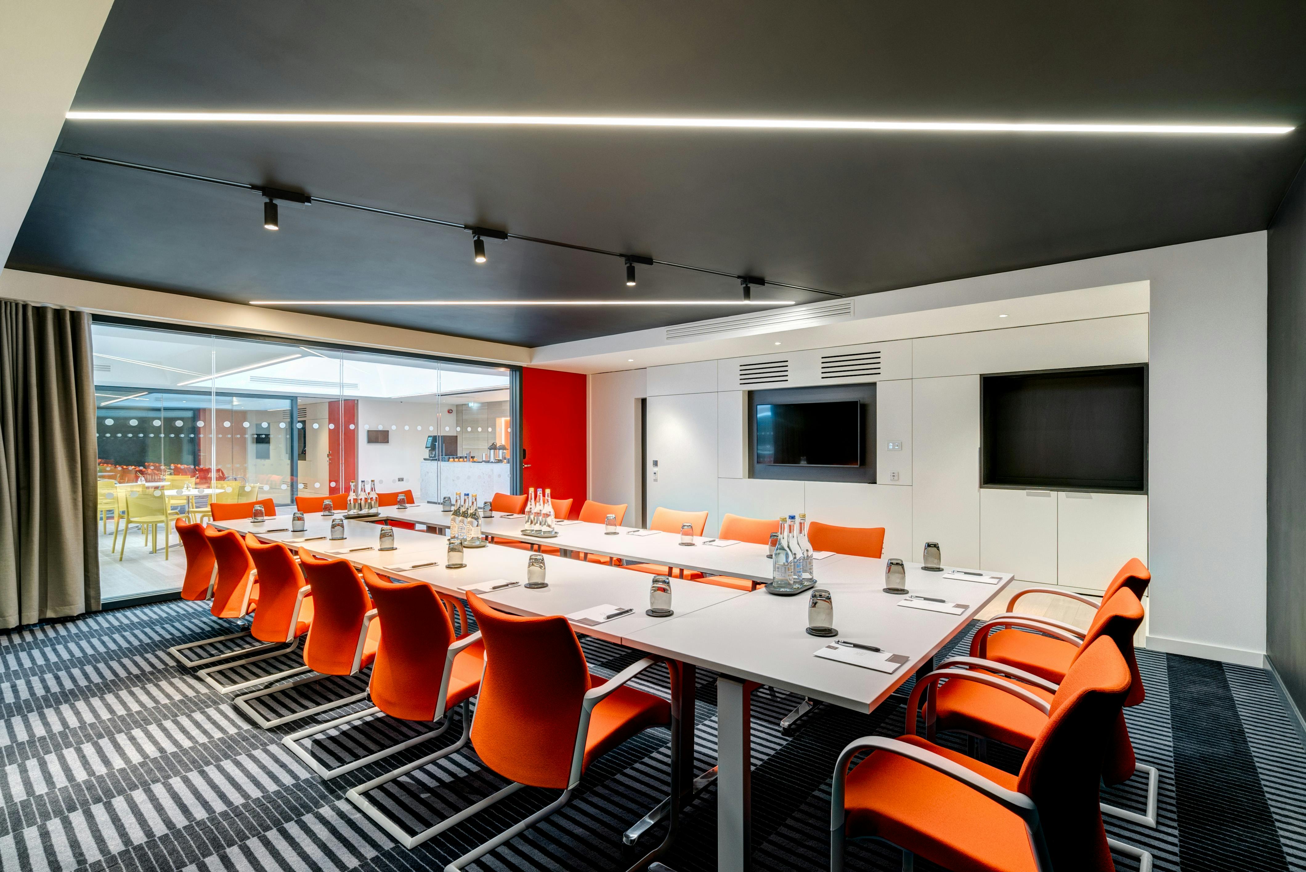 Modern conference room at Apex City of Bath Hotel with bright orange chairs for workshops.