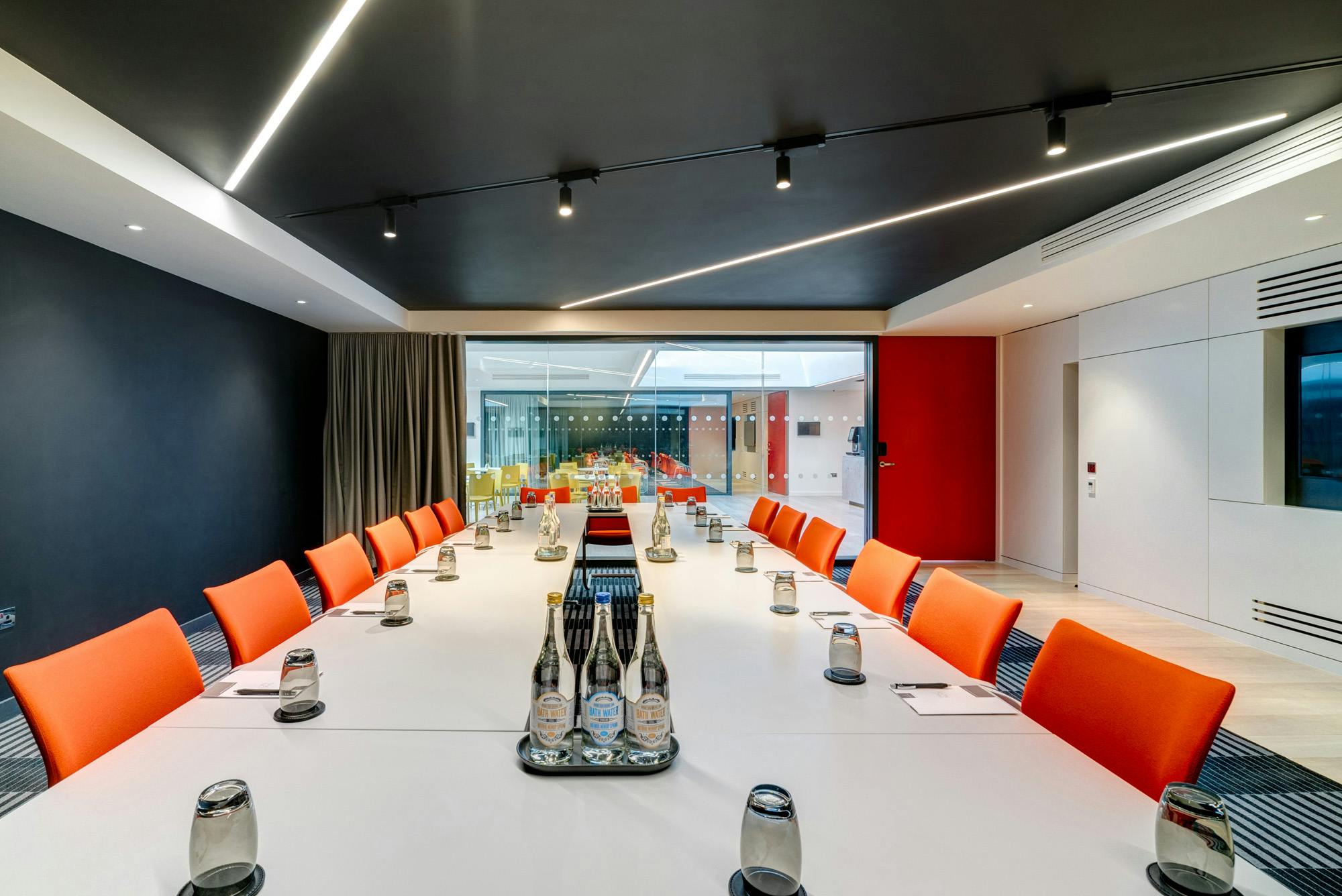 Modern meeting room in Bathwick with sleek table and vibrant orange chairs for events.