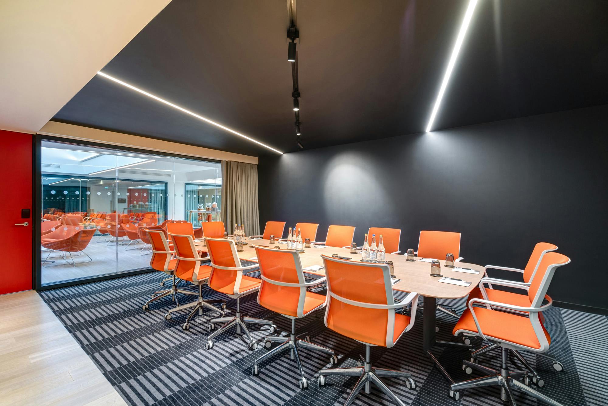 Modern conference room with oval table and orange chairs in Apex City of Bath Hotel.