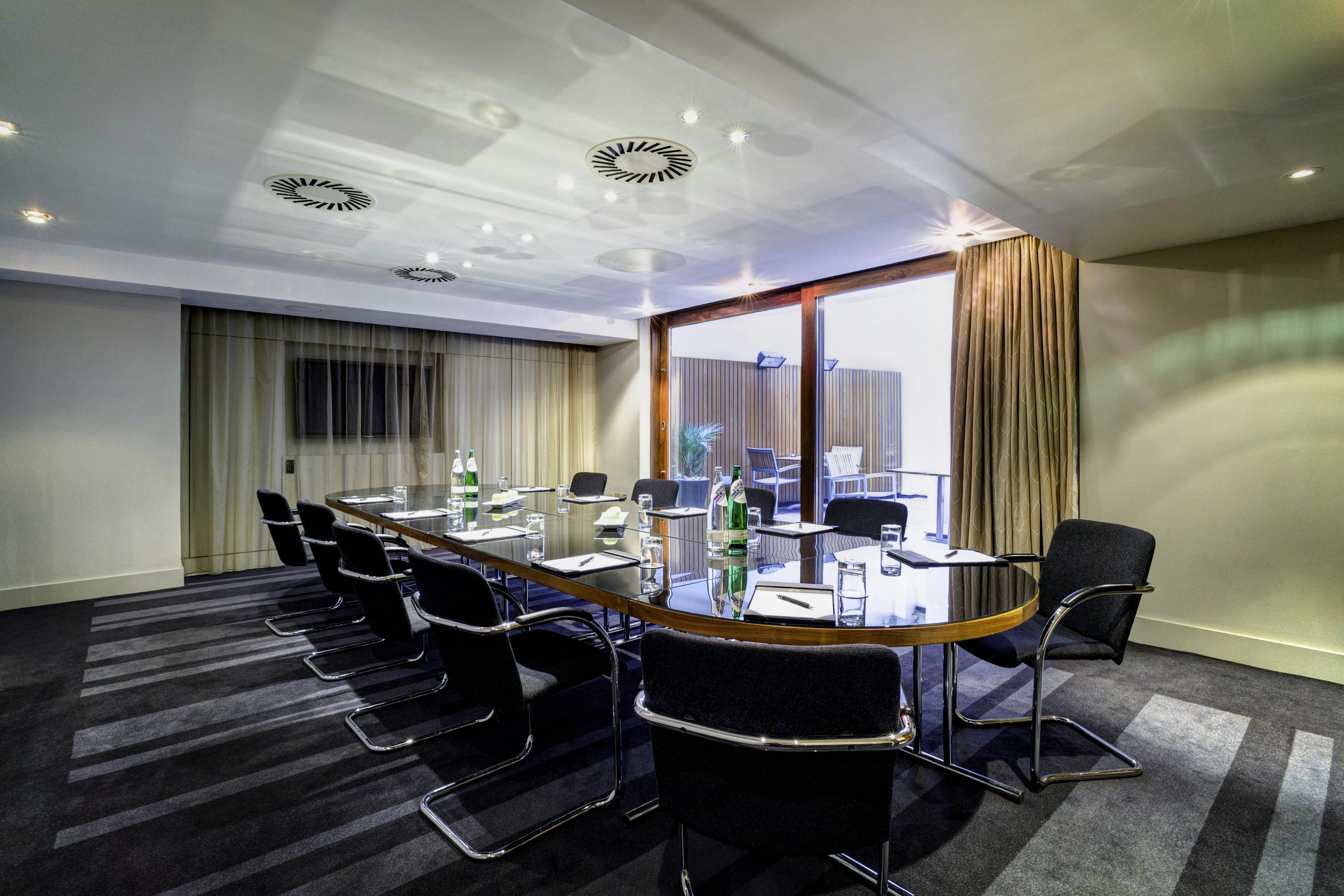 Modern meeting room in Apex City of London Hotel, featuring a sleek oval table.