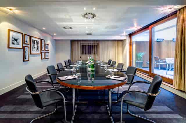 Modern meeting room in Apex City of London Hotel, featuring a sleek oval table and natural light.
