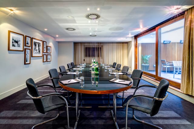 Modern meeting room in Apex City of London Hotel, featuring a sleek oval table and natural light.